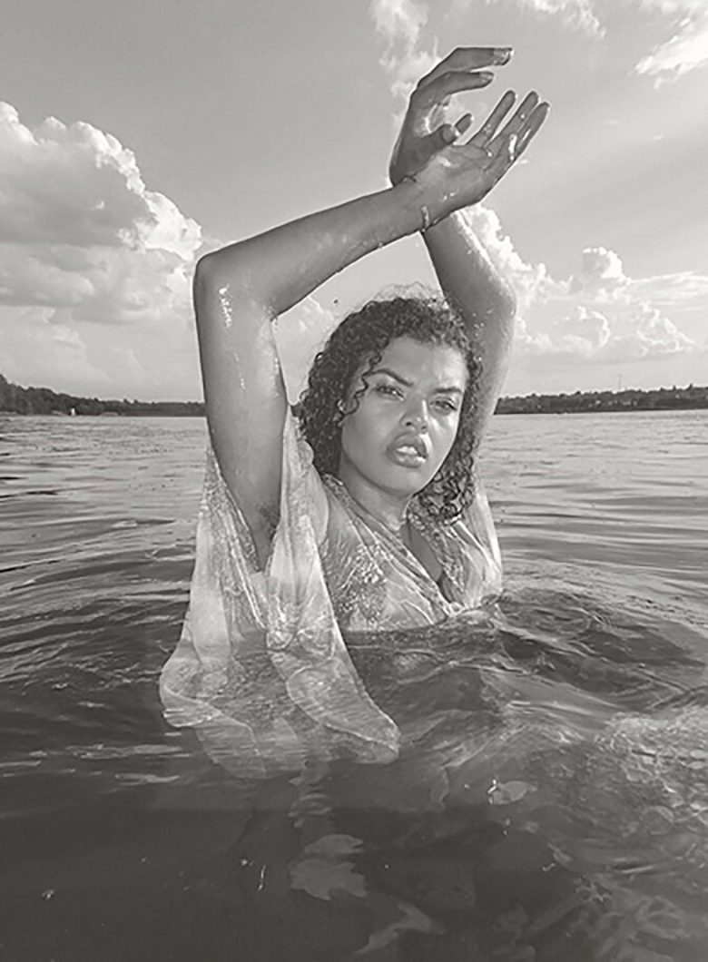 Portrait Sarah Barable Tishauer holding up crossed arms while wading in a lake.