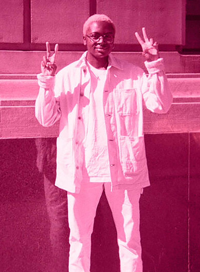 Full length portrait of Taymah Armatrading holding up peace signs with both hands.